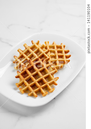 Belgian waffles on a white plate on a marble background. 141190104