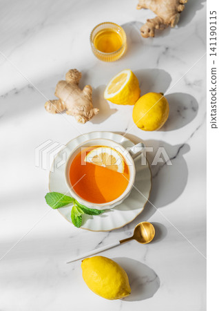Cup of tea with lemon, ginger and mint on a marble background with honey Cup of tea with lemon, ginger and mint on a marble background with honey 141190115