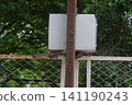 White electrical distribution box mounted on wooden pole behind wire mesh fence 141190243