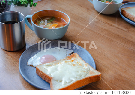 A breakfast set consisting of warm soup, a fried egg, and toast. 141190325