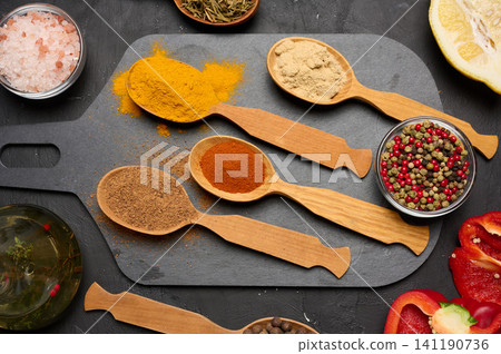 Assorted ground spices in wooden spoons, turmeric, paprika, nutmeg, ginger, dark stone surface Assorted ground spices in wooden spoons, turmeric, paprika, nutmeg, ginger, dark stone surface 141190736