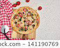 Round pizza with chicken and bacon on a wooden board 141190769
