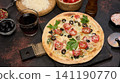Whole pizza on a wooden board surrounded by tomatoes, olives, herbs, spices and kitchen tools 141190770
