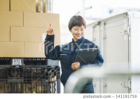 一位身穿工作服的年輕女子正在檢查貨物。 一位身穿工作服的年輕女子正在檢查貨物。 141191759