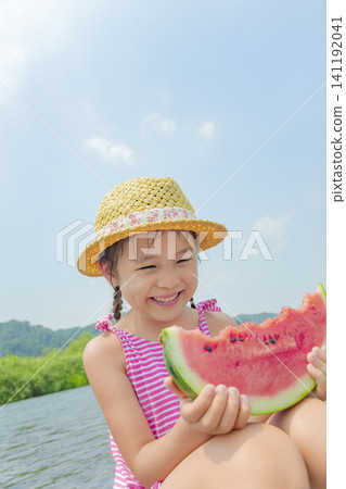 夏天,一個女孩在河邊吃西瓜。 夏天,一個女孩在河邊吃西瓜。 141192041