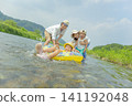 A family of four playing in the river in summer. 141192048