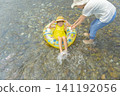 A girl and her mother playing in a river in summer 141192056