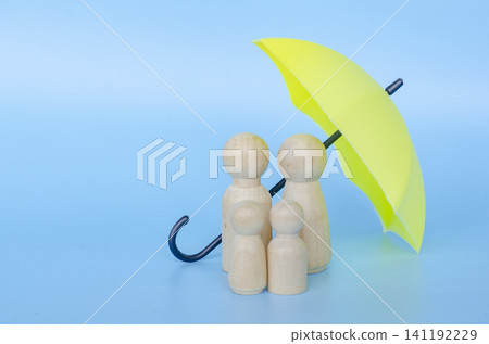 Wooden figures with a yellow umbrella representing security and insurance with customizable space for text. Wooden figures with a yellow umbrella representing security and insurance with customizable space for text. 141192229