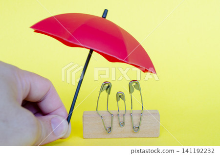 Hand holding red umbrella covering family member in pin form with customizable space for text. Hand holding red umbrella covering family member in pin form with customizable space for text. 141192232