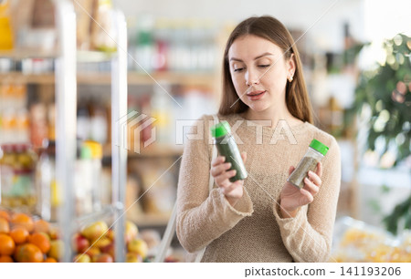 Girl shopping at supermarket - choosing ground pepper in grocery section supermarket Girl shopping at supermarket - choosing ground pepper in grocery section supermarket 141193206