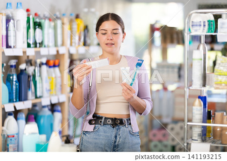 Positive beautiful young woman choosing toothpaste and toothbrush, oral care products in store Positive beautiful young woman choosing toothpaste and toothbrush, oral care products in store 141193215