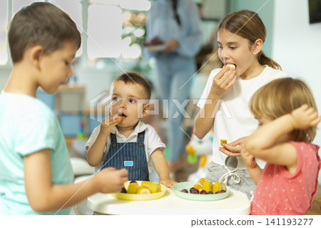 Children boys and girls eating fruit in kindergarten Children boys and girls eating fruit in kindergarten 141193277