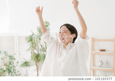 一位三十多歲的女性在客廳裡十分開心。 一位三十多歲的女性在客廳裡十分開心。 141193377