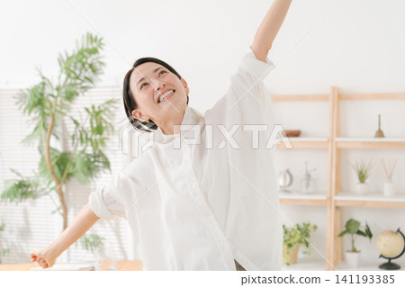 一位三十多歲的女性在客廳裡十分開心。 一位三十多歲的女性在客廳裡十分開心。 141193385