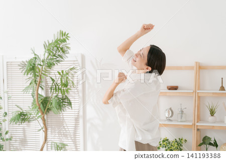 一位三十多歲的女性在客廳裡十分開心。 一位三十多歲的女性在客廳裡十分開心。 141193388