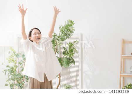 一位三十多歲的女性在客廳裡十分開心。 141193389