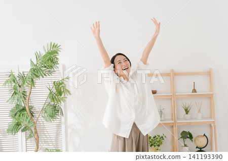 一位三十多歲的女性在客廳裡十分開心。 一位三十多歲的女性在客廳裡十分開心。 141193390