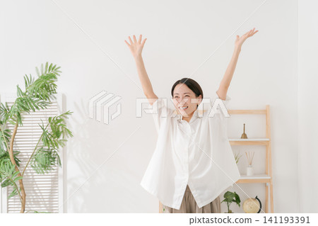 一位三十多歲的女性在客廳裡十分開心。 141193391