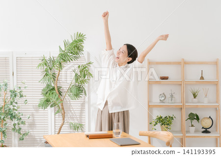 A woman in her 30s is delighted in her living room. A woman in her 30s is delighted in her living room. 141193395