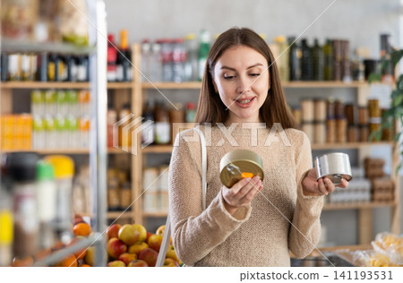Female shopper choosing canned food in grocery store Female shopper choosing canned food in grocery store 141193531