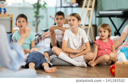 Children sit together and listen to the teacher Children sit together and listen to the teacher 141193582