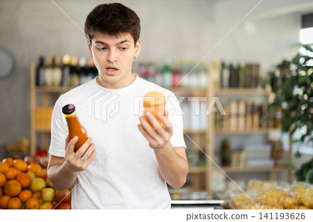 European guy looks at product and shop around, choose and buy sauce in shop European guy looks at product and shop around, choose and buy sauce in shop 141193626