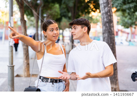 Positive tourist couple walking around foreign city on summer day, pointing at sights Positive tourist couple walking around foreign city on summer day, pointing at sights 141193667