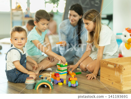 Children playing with toys with teacher nearby in kindergarten 141193691