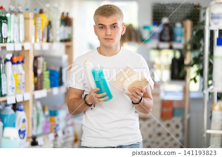Attentive smiling young guy buyer looking for body washcloth and shower gel in store Attentive smiling young guy buyer looking for body washcloth and shower gel in store 141193823