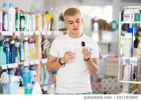Nice young man customer buying deodorant and choosing between two bottle in store Nice young man customer buying deodorant and choosing between two bottle in store 141193860
