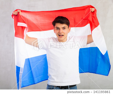 Smiling young guy holding Netherlands flag Smiling young guy holding Netherlands flag 141193861
