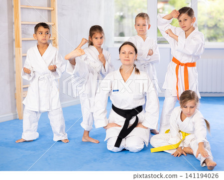 Team of young martial arts athletes is standing in gym with female coach. 141194026