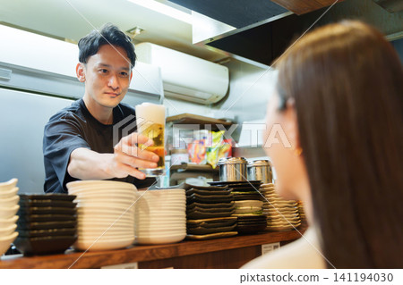 Manager serving beer to customers at an izakaya (Japanese pub) Manager serving beer to customers at an izakaya (Japanese pub) 141194030