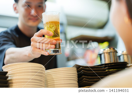 Manager serving beer to customers at an izakaya (Japanese pub) Manager serving beer to customers at an izakaya (Japanese pub) 141194031