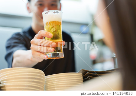 Manager serving beer to customers at an izakaya (Japanese pub) Manager serving beer to customers at an izakaya (Japanese pub) 141194033