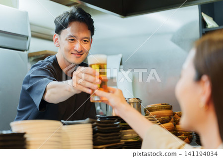 Manager serving beer to customers at an izakaya (Japanese pub) Manager serving beer to customers at an izakaya (Japanese pub) 141194034