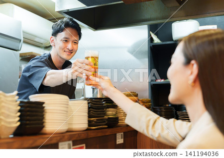 居酒屋(日式酒吧)經理為顧客倒啤酒 居酒屋(日式酒吧)經理為顧客倒啤酒 141194036