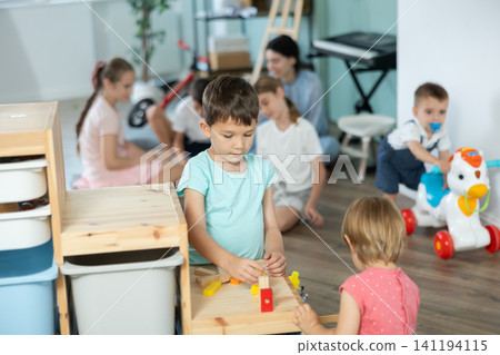 Little girl and older boy playing with wooden blocks on storage-shelf Little girl and older boy playing with wooden blocks on storage-shelf 141194115