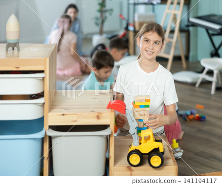 Girl playing with toys in front of children in kindergarten Girl playing with toys in front of children in kindergarten 141194117