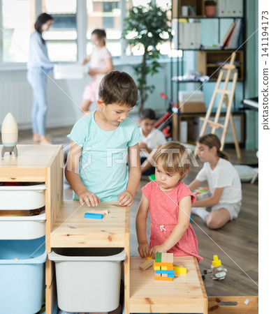 Little girl and older boy playing with wooden blocks on storage-shelf Little girl and older boy playing with wooden blocks on storage-shelf 141194173