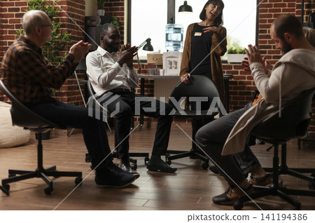 Multiethnic participants applauding woman in support meeting as a therapy circle encourages honest discussion, emotional support and addiction recovery progress. Multiethnic participants applauding woman in support meeting as a therapy circle encourages honest discussion, emotional support and addiction recovery progress. 141194386