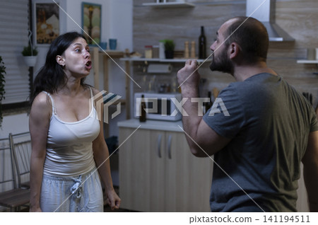 Husband and wife shout during an aggressive home conflict, showing domestic violence, social problems and a threatening relationship dispute. Husband and wife shout during an aggressive home conflict, showing domestic violence, social problems and a threatening relationship dispute. 141194511