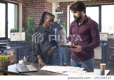 Professional man with tablet discusses business plans with a pregnant coworker, supporting research, strategy and project presentation work. Professional man with tablet discusses business plans with a pregnant coworker, supporting research, strategy and project presentation work. 141194537