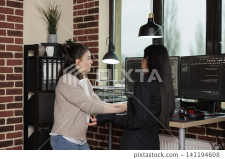 Company programmers stand beside a desk of multiple monitors while updating firewall systems and processing network information layers. Company programmers stand beside a desk of multiple monitors while updating firewall systems and processing network information layers. 141194608