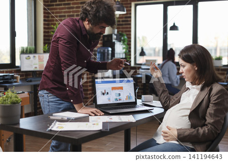 Pregnant office worker questions business analytics and data charts while informing a finance manager about a weak project strategy at her desk. Pregnant office worker questions business analytics and data charts while informing a finance manager about a weak project strategy at her desk. 141194643