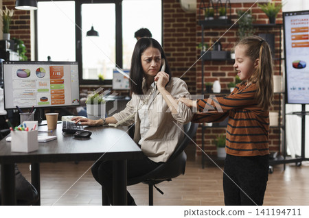 Mother handles office phone call near daughter, working woman annoyed by irritating little daughter while talking on phone in company office. 141194711