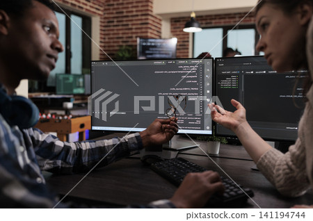 Network developers update a firewall system through layered security information processing while working near desks and multiple monitors. Network developers update a firewall system through layered security information processing while working near desks and multiple monitors. 141194744