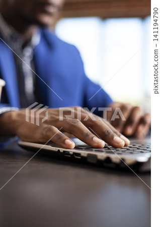 Hands of african american employee typing on laptop at startup office desk, Black male individual updating company research data using digital technology for work tasks. Hands of african american employee typing on laptop at startup office desk, Black male individual updating company research data using digital technology for work tasks. 141194790