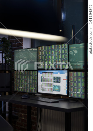 Vacant office workstation displays forex charts across multiple monitors, showing financial data and a prepared trading setup for night shift employees. Vacant office workstation displays forex charts across multiple monitors, showing financial data and a prepared trading setup for night shift employees. 141194842