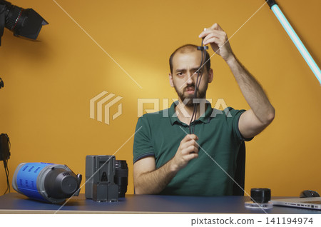 Content creator reviews USB Type C cable in professional studio while explaining lighting equipment, modifier use and practical studio production for online video subscribers. Content creator reviews USB Type C cable in professional studio while explaining lighting equipment, modifier use and practical studio production for online video subscribers. 141194974